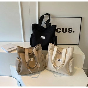 Detailed view of canvas tote bags in black, khaki and off-white with side zippers