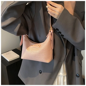 Détail du sac sous l'aisselle en tissage rose avec logo en métal et bandoulière