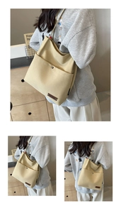 Detail of light yellow canvas tote bag featuring front pocket with metal magnetic snap button