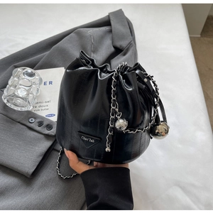 Close-up of black bucket bag with silver metal ball charm and drawstring detail