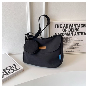 Detail of black canvas shoulder bag with small round pouch and brown leather logo tag