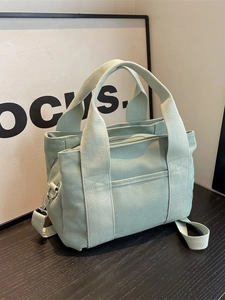 Minimalist light green canvas tote bag with multi-pocket design and adjustable strap