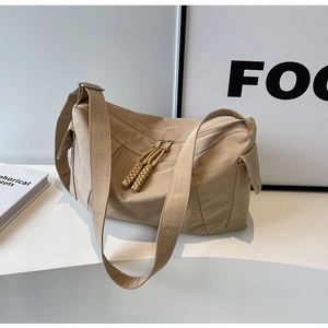 Dettaglio della borsa a tracolla in tela kaki con cerniere e tasche laterali a patta