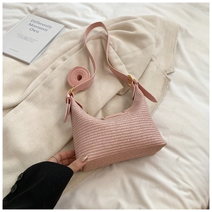 Détail du sac en paille tissée rose avec bandoulière cuir et boucle dorée