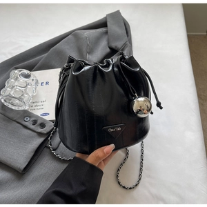Black bucket bag with vertical texture, chain strap, drawstring closure and logo plate