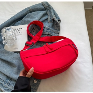 Detail of red nylon crescent crossbody bag styled with a blue denim jacket background