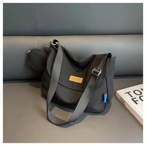 Detail of black canvas messenger bag featuring a small round pouch and adjustable strap