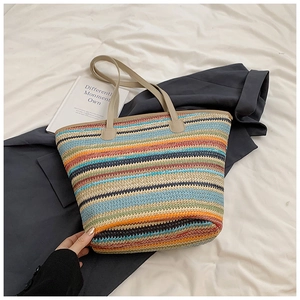 Detail of colorful striped straw tote bag with beige leather handles and woven texture