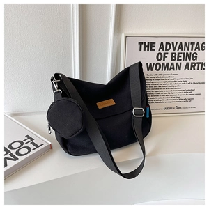 Close-up of black canvas bag with leather logo patch and detachable coin purse accessory