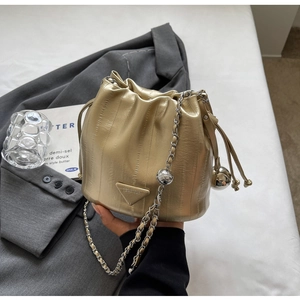 Detailed view of champagne gold bucket bag with metallic texture and chain strap