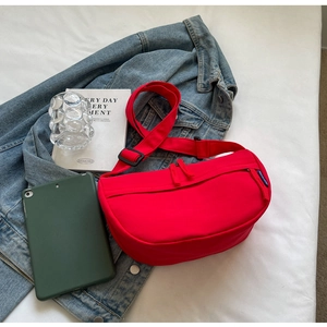 Macro detail of red nylon crescent bag with smooth zipper and adjustable strap