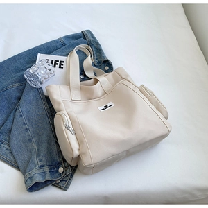 Detail of beige canvas tote bag with fashion label and zipper pocket in a lifestyle setting