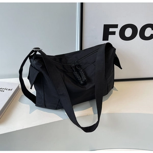 Dettaglio della borsa a tracolla in nylon nero con doppia cerniera e tiranti intrecciati