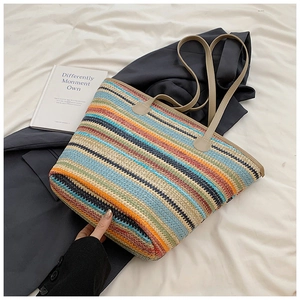 Detail of colorful striped woven tote bag with leather handles on grey blazer