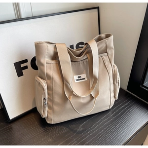 Detailed macro view of beige canvas tote bag with front FASHION patch and side zippers