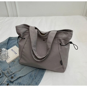 Detail of adjustable side drawstring and brand tag on a gray nylon tote bag