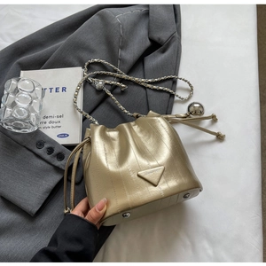 Close-up of golden metallic bucket bag with drawstring closure and metal ball charms