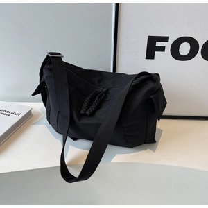 Dettaglio borsa in nylon nero con tiranti della zip intrecciati e tracolla larga regolabile