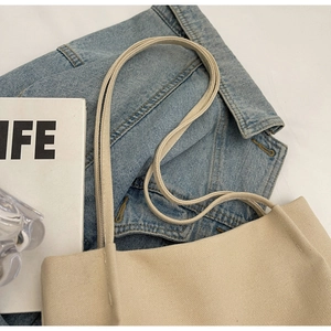 Close-up of beige canvas bucket bag texture with neat stitching and shoulder straps
