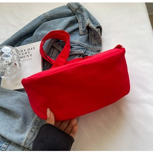 Close-up of vibrant red canvas crossbody bag with matching strap on white background