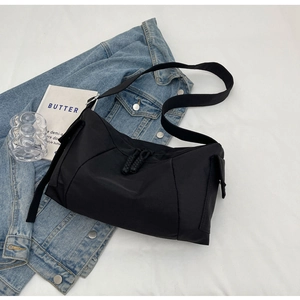 Dettaglio della borsa a tracolla in nylon nero con cuciture geometriche e zip intrecciate