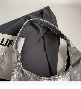Close-up of metallic silver hobo bag showing wrinkled texture and wide shoulder strap