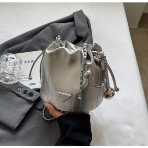 Macro detail of silver pleated bucket bag with metallic chain and drawstring closure