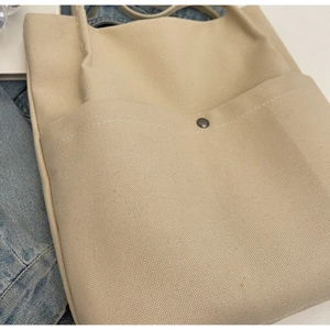 Detail of canvas bucket bag showing large front pocket and precise stitching texture