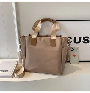 Close-up of khaki nylon tote bag with side pocket and golden hardware for daily commute