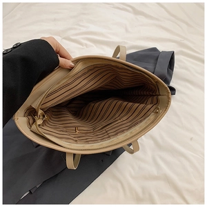Interior detail of large tote bag with striped lining and gold zip pocket storage