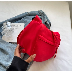 Close-up of red nylon crossbody bag with curved design and durable fabric texture