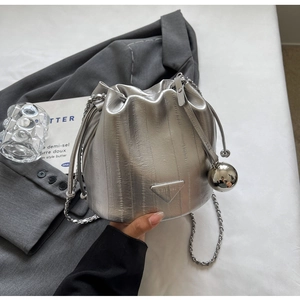 Detail of silver metallic bucket bag with chain strap and triangular logo plaque