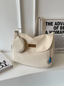 Minimalist beige canvas crossbody bag with round coin purse and wide strap on white background