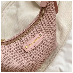 Détail du sac tissé rose avec étiquette en cuir et fermeture éclair dorée chic