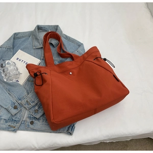 Detail view of large orange nylon tote bag with drawstring and magnetic closure