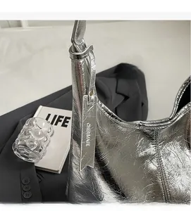Detail of silver metallic wrinkled texture shoulder bag with brand tag and minimalist props