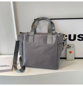 Detail of grey quilted nylon tote bag with golden hardware and adjustable shoulder strap