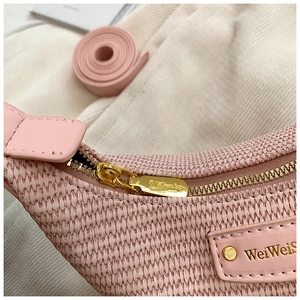 Détail du sac tissé rose montrant la fermeture éclair dorée et l'étiquette en cuir
