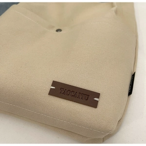 Close-up of canvas bucket bag featuring leather logo tag and fine stitching details