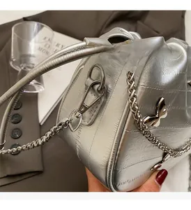 Détail du sac seau argenté avec matelassage ondulé et fermoir papillon en métal