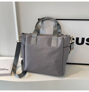Close-up of gray tote bag with nylon texture, gold hardware, and detachable strap