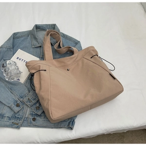 Detail of khaki nylon tote bag with side drawstrings and smooth texture for daily use