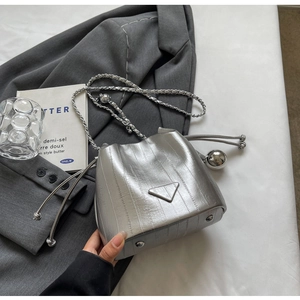 Detail of silver bucket bag with vertical texture, metallic chain and drawstring ball charm