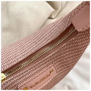 Gros plan sur la texture tressée rose avec fermeture dorée et logo en cuir du sac