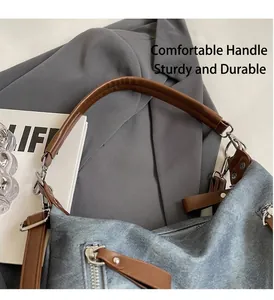 Detail einer blauen Denim-Tragetasche mit robusten braunen Ledergriffen und Silberbeschlägen