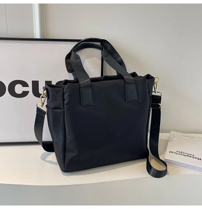Detail view of black nylon tote bag showing side pocket and golden metal hardware