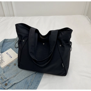 Detail of black nylon tote bag showing metal magnetic closure and durable side drawstrings