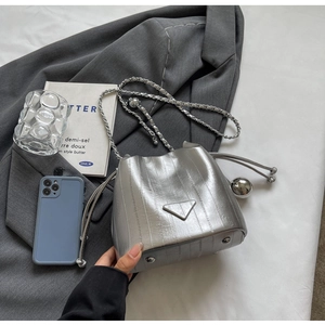 Macro shot of silver metallic bucket bag with drawstring chain and triangle logo