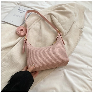 Détail de la texture tissée rose d'un sac à bandoulière demi-lune avec sangle en cuir