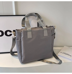 Detail of grey puffer tote bag showing texture, side pockets, and adjustable shoulder strap